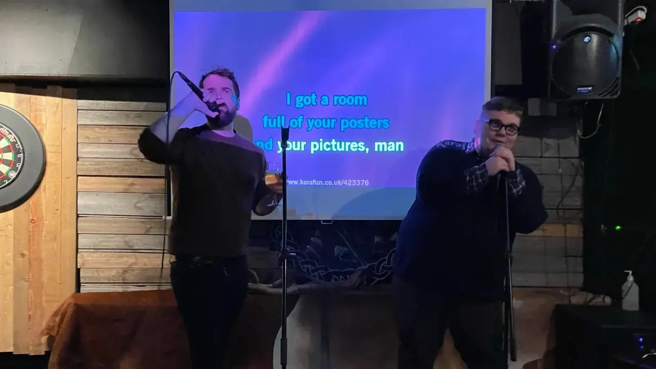 Photograph of two Arctic Theory team members singing karaoke together